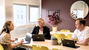 tre kolleger sitter rundt ett bord og snakker sammen
