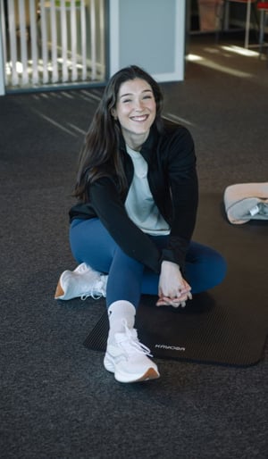 Person som sitter på treningsmatte og smiler