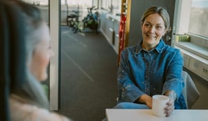 To personer som snakker sammen og drikker kaffe